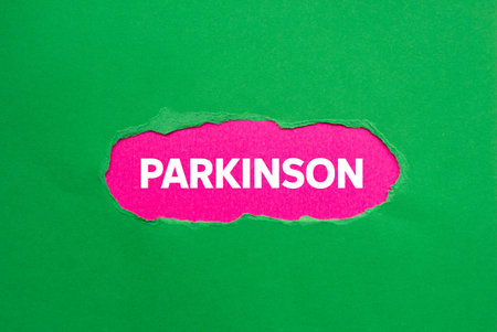 Parkinson message written on ripped torn green paper on pink background. Conceptual parkinson symbol. Copy space.の写真素材