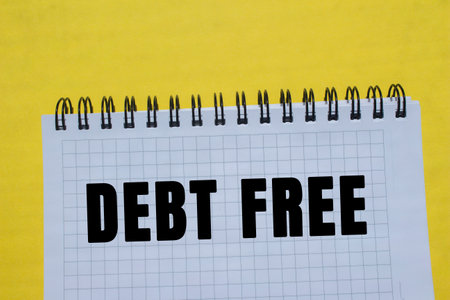 Debt free message written on notebook page on yellow background. Conceptual debt free symbol. Copy space.の写真素材