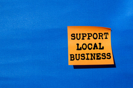 Support local business message written on orange paper on blue background. Conceptual support local business symbol. Copy space.の写真素材