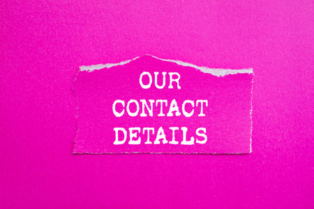 Our contact details message written on ripped torn pink paper piece on pink background. Conceptual our contact details symbol. Copy space.の写真素材