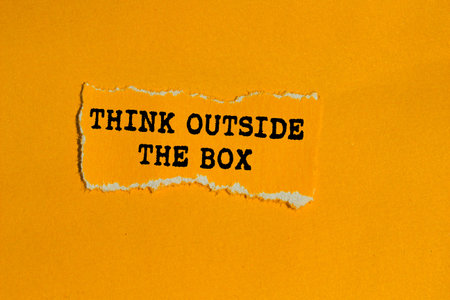 Think outside the box message written on ripped torn orange paper piece on orange background....