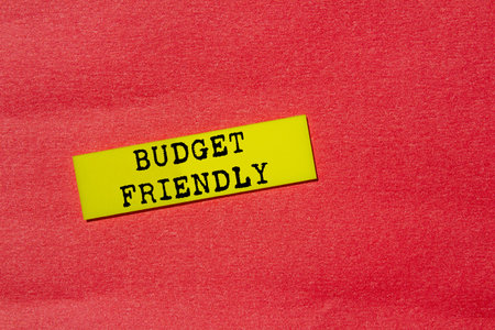 Budget friendly message written on yellow paper label on red background. Conceptual budget friendly...
