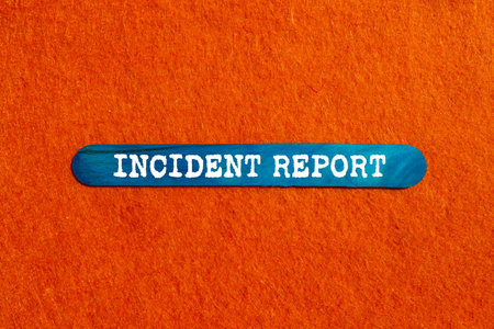Incident report message written on blue wooden stick on orange background. Conceptual incident report symbol. Copy space.の写真素材