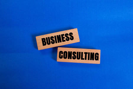 Business consulting message written on wooden blocks on blue background. Conceptual business consulting symbol. Copy space.の写真素材
