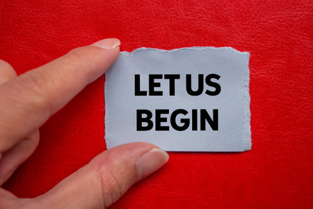 Let us begin message written on ripped torn gray paper piece on red background. Conceptual let us begin symbol. Copy space.の写真素材