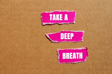 Take a deep breath message written on ripped torn pink paper pieces on cardboard background. Conceptual take a deep breath symbol. Copy space.の写真素材