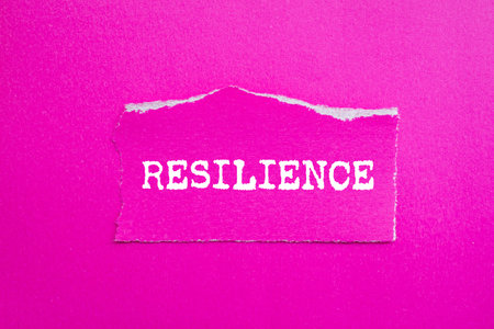 Resilience message written on ripped torn pink paper piece on pink background. Conceptual resilience symbol. Copy space.の写真素材
