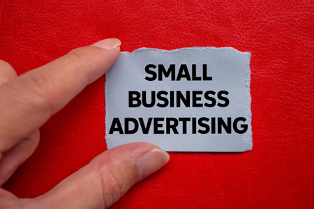 Small business advertising message written on ripped torn gray paper piece on red background. Conceptual small business advertising symbol. Copy space.