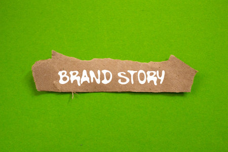 Brand story message written on ripped torn brown paper piece on green background. Conceptual brand story symbol. Copy space.の写真素材