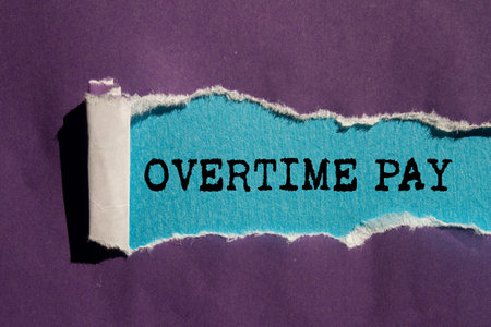 Overtime pay message written on ripped torn purple paper on blue background. Conceptual overtime pay symbol. Copy space.の写真素材
