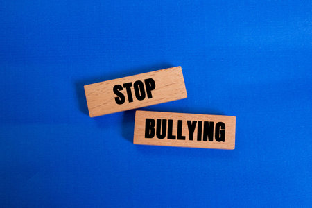 Stop bullying message written on wooden blocks on blue background. Conceptual stop bullying symbol....