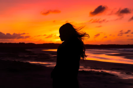 silhouette of a girl on the background of the sea sunset sky generative ai.の素材