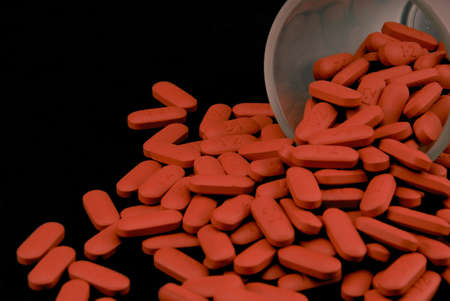 Pills pouring from a shot glass with black background.の写真素材