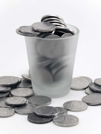 Various coinage strewn around a shot glass.の写真素材