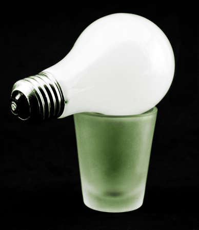 A lightbulb on top a green-lit shotglassの写真素材
