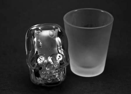 A skull toy next to a shot glassの写真素材