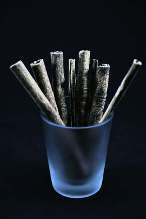 Cinnamon sticks in a shot glass, edited to look like cigarrettesの写真素材