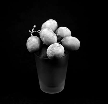 A few grapes rested atop a shot glassの写真素材