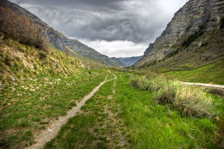 An old dirt trail through provo canyon with a looming sky in backgroundの写真素材