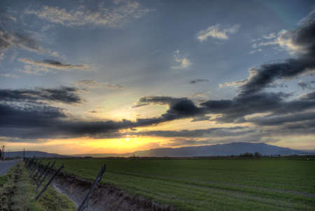 A high dynamic range shot of sunset over a green field.の写真素材
