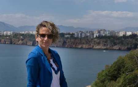 Young woman with city and sea view in the background. Spring. Daytime.