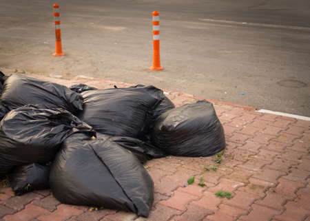 Pile of black full garbage bags down on the pavement.の写真素材