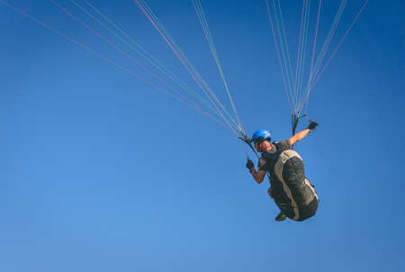 Man on parachute. Paraglider in the air, close image of a sportsman maneuvering.