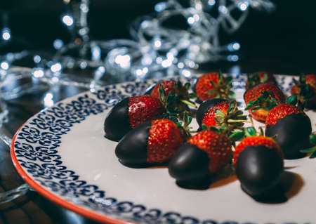 Strawberries on the plate covered with chocolate and decorated with lights. Close image of strawberries ready to serve.の写真素材
