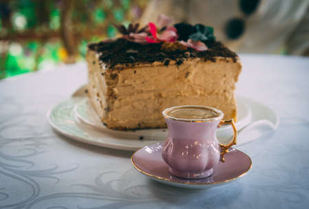 Homemade cake decorated with flowers. On the table with cup of Turkish coffee in front.の写真素材