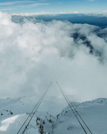 Cables of funicular go into clouds. View from top of the mountain.の写真素材
