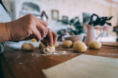 Forming dough balls for baking buns on the wooden table.Hands of a woman in the kitchen shaping dough balls.の写真素材