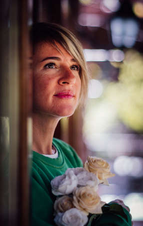 Portrait of a pretty blonde woman with bouquet. Beautiful young lady posing with flowers.の写真素材