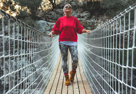 Adult woman standing on a hanging wooden bridge in the nature. Female hiker in Goynuk Canyon in Antalya, Turkey.の写真素材