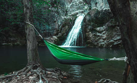 Green hammock with person in it between trees in front of a waterfall in Eksili, Antalya, Turkey.の写真素材