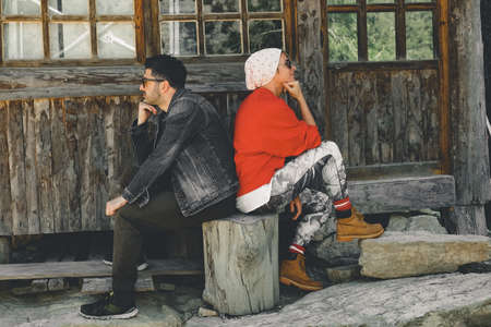 Couple sitting back to back in front of the house Two sulky adults turned away from each other.