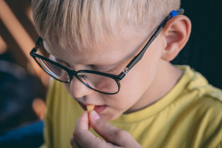 Cute little boy with glasses eating french fries. Selective focus.
