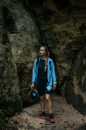 Young woman hiker standing in a cave and looking at the cameraの写真素材