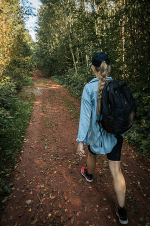 Young woman with backpack walking in the forest. Healthy lifestyle concept.の写真素材