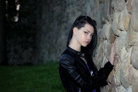 View of a beautiful girl in classic costume next to a stone wall.