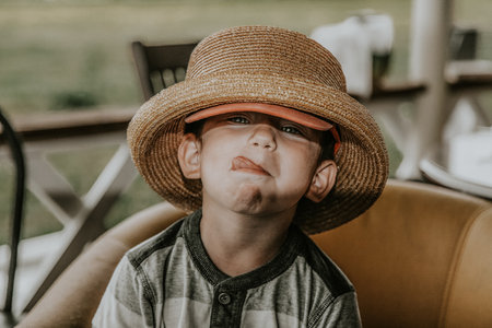 Portrait of a boy in a straw hat sitting in a cafeの写真素材