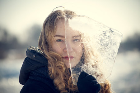 Winter portrait of a beautiful young woman with ice on her face.の写真素材