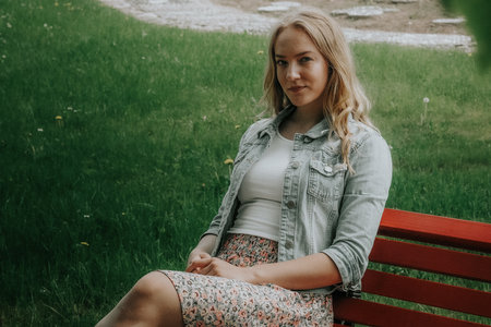Portrait of a beautiful blonde girl sitting on a bench in the parkの写真素材