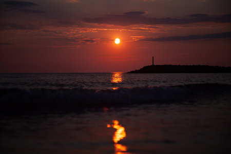 Sunset over the sea with a lighthouse in the background. Silhouette of a lighthouse at sunset.の写真素材
