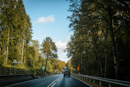 Car driving on the road in the autumn forest. Concept of traveling by car.の写真素材
