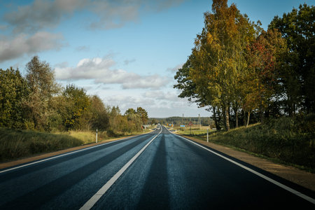 Autumn landscape with empty asphalt road and blue sky with clouds.の写真素材