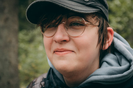 Portrait of a young man with glasses and a cap in the park