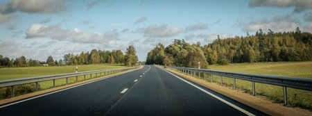 Panoramic view of an empty road in the countryside with blue skyの写真素材