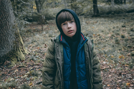 Portrait of a boy in the forest. A boy in a jacket with a hood.の写真素材