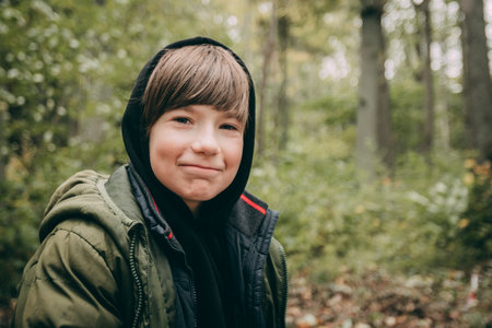 portrait of a boy in a green jacket in the autumn forestの写真素材