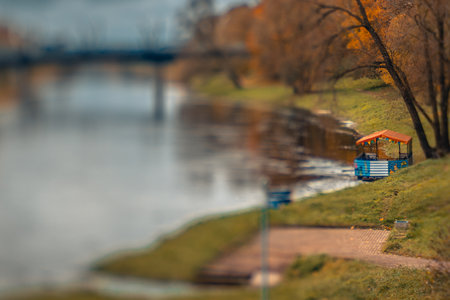 Autumn landscape with river, trees and bench in the park.の写真素材